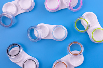 A lot of contact lens containers on a blue background. Top view.