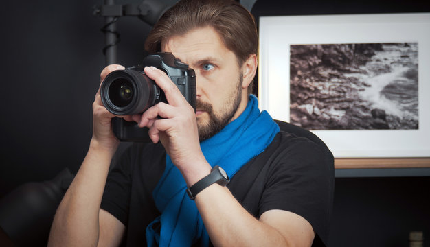 Close-up of male photographer taking pictures with digital camera indoors, front view