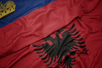 waving colorful flag of albania and national flag of liechtenstein.