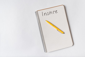 INSPIRE handwriting notice. Top view of Notepad and pen on white background.