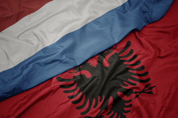 waving colorful flag of albania and national flag of luxembourg.