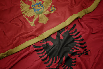 waving colorful flag of albania and national flag of montenegro.