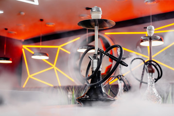 Black hookah and hookah with a transparent cup in the smoke on the table in a restaurant on the...