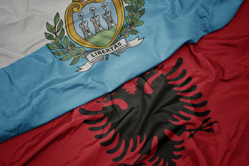 waving colorful flag of albania and national flag of san marino.