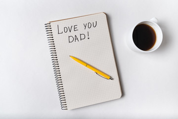 Cute inscription in notebook I LOVE YOU DAD. Coffee, notepad and pen. Top view
