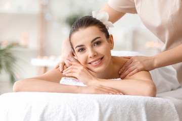 Beautiful young woman receiving massage in spa salon