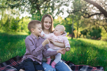 Naklejka na ściany i meble Older brother and little sister and the Park. Family picnic on nature. Motherhood and childhood