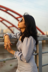 A young beautiful girl poses on an old bridge.