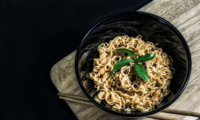 Instant noodles in a bowl on a black background