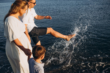 stylish man and his wife and their little son relaxing by the sea at sunset. Photo from a real...