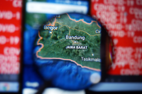 Bandung, West Java/Indonesia on google maps under magnifying glass with Red Covid-19 text Background.  