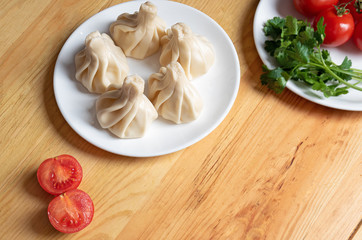 khinkali on a white plate  and fresh vegetables close-up. Dish of Georgian cuisine