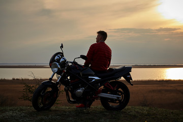 Fototapeta na wymiar young man with a motorcycle at sunset