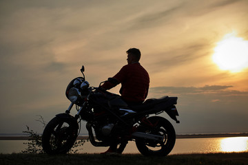 Fototapeta na wymiar young man with a motorcycle at sunset