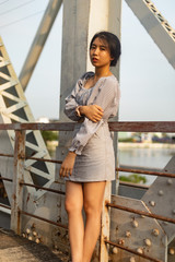 A young beautiful girl poses on an old bridge.