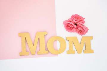 top view of roses and mom lettering on pink and white background