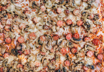 Pizza with sausages and mushrooms, onions and tomato paste. Close up, top view. Stage of preparation before sprinkling with cheese.