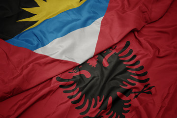 waving colorful flag of albania and national flag of antigua and barbuda.