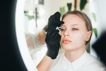 Dyeing and shaping of eyebrows. girl in a beauty salon. plucking eyebrows with tweezers