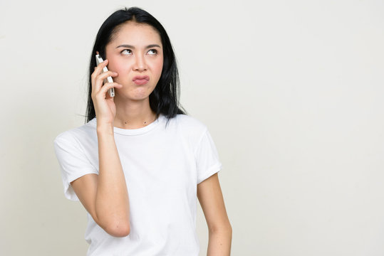 Portrait of stressed young Asian woman talking on the phone