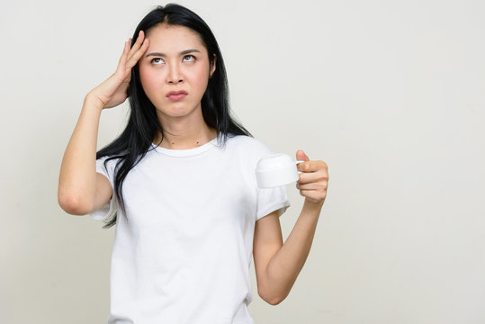 Portrait Of Stressed Young Asian Woman Holding Coffee Cup Upside Down