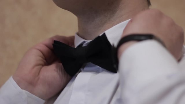 a man puts a bow tie around his neck