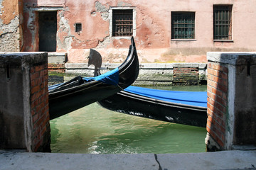 Fototapeta na wymiar Two gondolas at the pier in the Venetian canal on a summer day. Close-up. Venice, Italy.