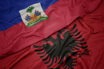 waving colorful flag of albania and national flag of haiti.