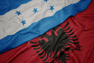 waving colorful flag of albania and national flag of honduras.