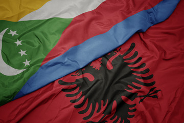 waving colorful flag of albania and national flag of comoros.