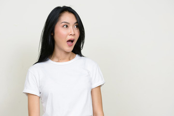 Portrait of young beautiful Asian woman looking shocked