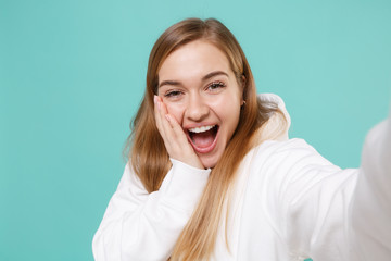 Close up of excited young woman girl in casual white hoodie isolated on blue turquoise background....