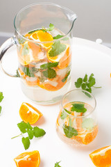 glass with a drink with orange and mint on a white background
