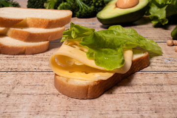 Appetizing simple sandwich with bread, cheese and lettuce. Homemade delicious food.