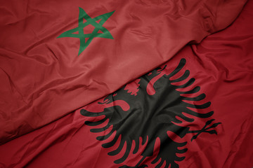 waving colorful flag of albania and national flag of morocco.