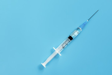 One disposable syringe on a blue background. Space for text.
