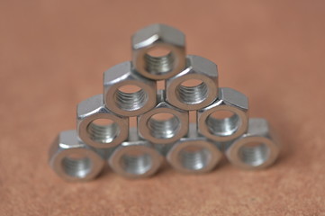 A pyramid of shiny, new female screws in fron of a blurred background.	