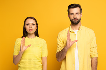 Young couple showing gesture in sign language on yellow background