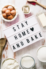 Stay home and bake covid 19 conceptual image for coronavirus pandemia,  with a lightbox texting stay home and bake,circled by tools and ingredients for baking bread and cake during quarantine,top view
