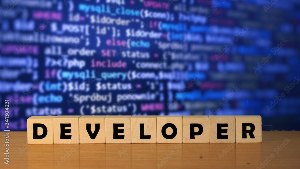 Poster developer message word on a wooden desk on cube blocks with a green nature background.