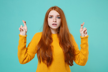 Shocked young redhead girl in yellow sweater isolated on blue turquoise wall background. People...