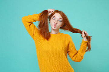 Crazy young redhead woman girl in yellow sweater isolated on blue turquoise background. People...