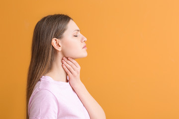 Young woman checking thyroid gland on color background