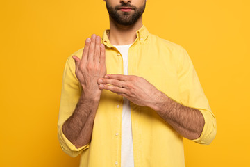 Cropped view of man showing gesture from sign language on yellow background