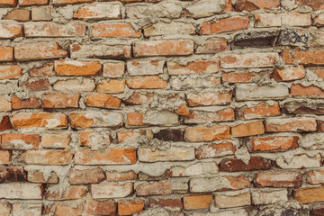 old brick wall, crooked brown bricks, uneven seams, brickwork collapsed