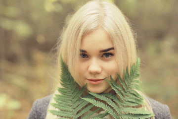 eco concept girl portrait fern, young adult model blonde, green leaf on face
