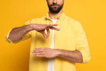 Cropped view of man gesturing while using sign language on yellow background