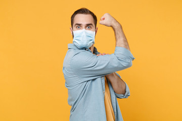 Side view of strong young man in sterile face mask posing isolated on yellow background in studio....