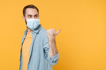 Side view of young man in sterile face mask posing isolated on yellow wall background studio...