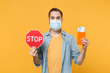 Young man in sterile face mask posing isolated on yellow background in studio. Epidemic pandemic...